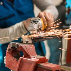 Technician worker cutting metal with many sharp sparks. Using equipments to cat iron